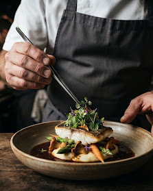 Les mains du chef dressant une assiette.